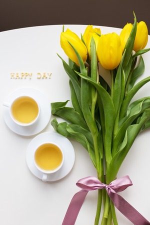 Beautiful yellow tulips on the table, the inscription happy dayの写真素材