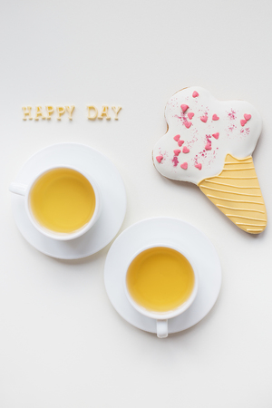 two cups of coffee on a table with cookies in the form of ice, inscription happy dayの写真素材