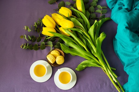 Yellow tulips and two cups of tea in bedの写真素材