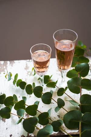 eucalyptus branches on an old table with a glass of rose wineの写真素材