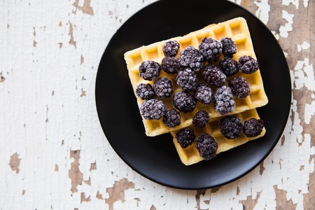 Belgian waffles with blackberry on an old wooden table.の写真素材