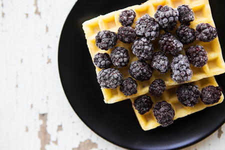 Belgian waffles with blackberries on the old wooden table, close-up.の写真素材