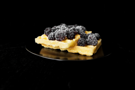 Belgian wafers with frozen blackberries on a black background.の写真素材