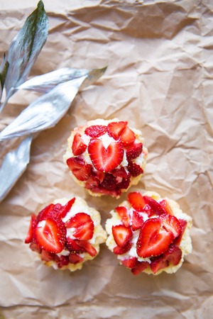 Beautiful cupcakes with strawberries along with a branch on kraft paper.の写真素材
