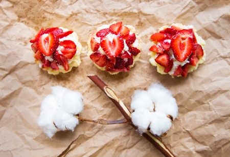 Beautiful cupcakes with strawberries along with a branch of cotton lies on kraft paper.の写真素材