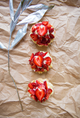Beautiful cupcakes with strawberries along with a branch on kraft paper.の写真素材