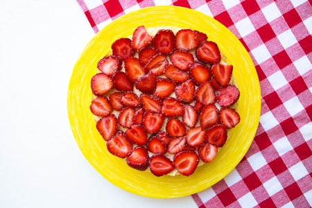 Bright and delicious strawberry cake on a red napkin in a cage.の写真素材