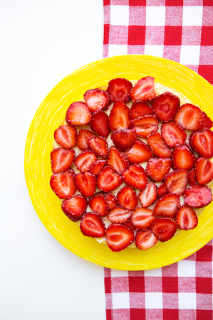 Bright and delicious strawberry cake on a red napkin in a cage.の写真素材