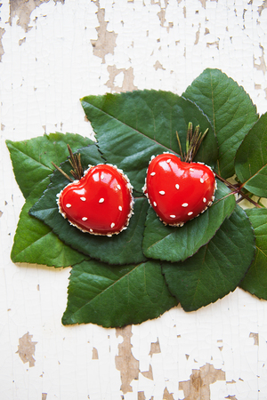 Dessert in the form of heart lies on green leaves on an old wooden background, close-up.の写真素材