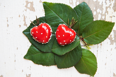 Dessert in the form of heart lies on green leaves on an old wooden background, close-up.の写真素材