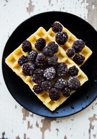 Belgian waffles with blackberry on an old wooden table.の写真素材