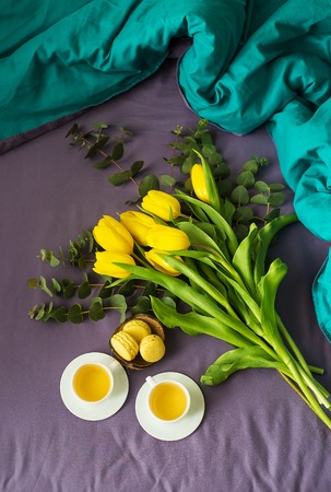 yellow tulips, cookies and two cups of tea in bed, close-upの写真素材