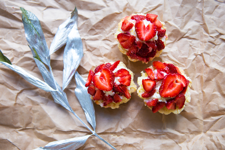 Beautiful cupcakes with strawberries along with a branch on kraft paper.の写真素材