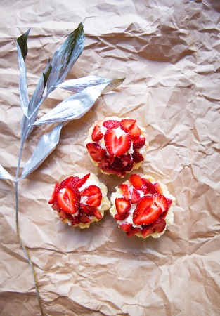 Beautiful cupcakes with strawberries along with a branch on kraft paper.の写真素材