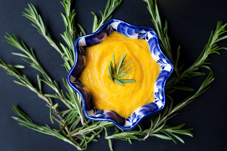 pumpkin soup on a black background with the sprigs of rosemary, close-upの写真素材