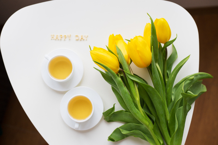 Beautiful yellow tulips on the table, the inscription happy dayの写真素材