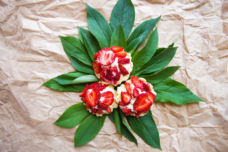 Beautiful and bright cupcakes with strawberries lie on green leaves.の写真素材
