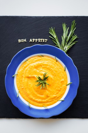 pumpkin soup in a blue plate on a black background with a blue napkinの写真素材