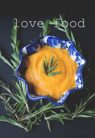 pumpkin soup on a black background with the sprigs of rosemary, inscription love foodの写真素材