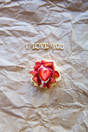 Bright cupcake with strawberries lies on craft paper, the inscription I love you.の写真素材