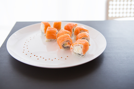 Sushi roll with salmon, philadelphia on a white plate on a black background top viewの写真素材