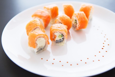 Sushi roll with salmon, philadelphia on a white plate, top view. Close-up. Beautifully decorated plateの写真素材