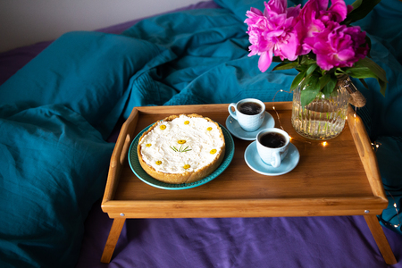 Coffee, pink peonies, cheesecake on a wooden tray, top view.の写真素材