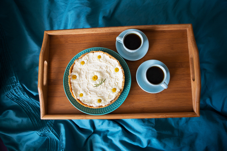Two cups of coffee and cheesecake stand on a wooden tray, top viewの写真素材