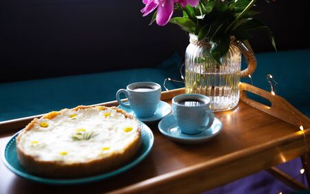 Breakfast in bed. Beautiful peonies, delicious cheesecake and two cups of coffee on a wooden trayの写真素材