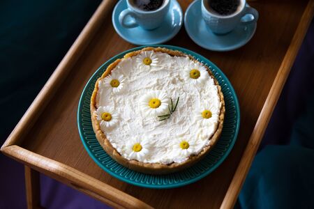 Top view - breakfast in bed a delicious cheesecake and two cups of coffee are on a wooden trayの写真素材