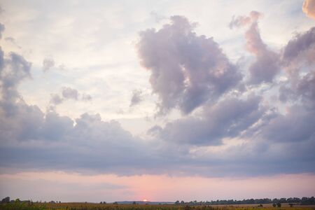 large clouds, beautiful sunset over an agricultural green field.の写真素材