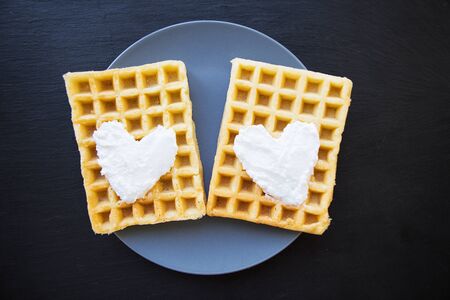 Delicious belgian waffles with cream on a black backgroundの写真素材