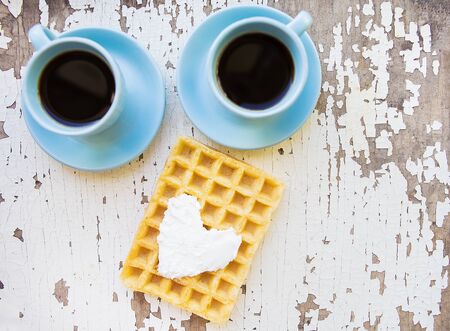 Belgian waffle and two cups of coffee on an old wooden tableの写真素材