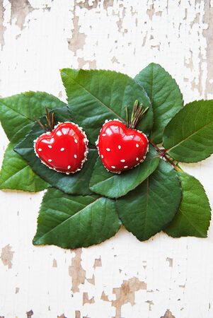 Dessert in the form of heart lies on green leaves on an old wooden background, close-up.の写真素材