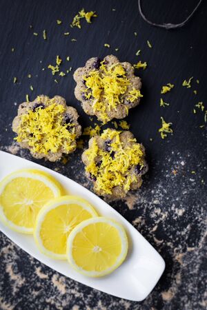 lemon cupcakes on a black background and a lemon on a plateの写真素材