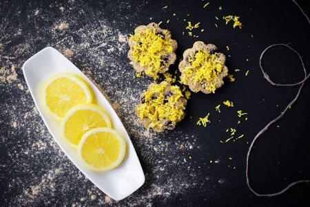 lemon cupcakes on a black background and a lemon on a plateの写真素材