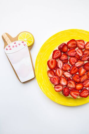 A bright and tasty strawberry cake stands on the table along with cookies in the form of a cocktail.の写真素材