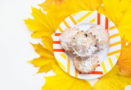 colored cupcakes on a plate and yellow autumn leaves, close-upの写真素材