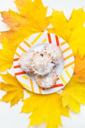 colored cupcakes on a plate and yellow autumn leavesの写真素材