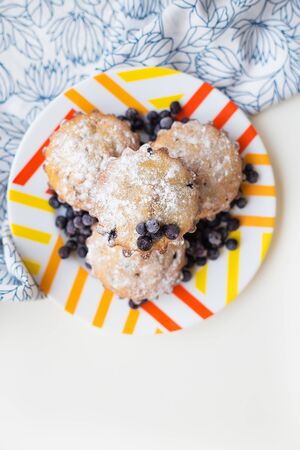 Blueberry muffins on plate and bright floral clothの写真素材