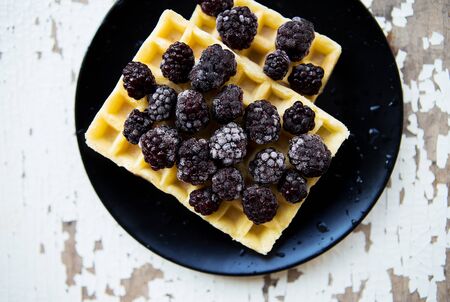 Belgian waffles with blackberry on an old wooden table.の写真素材