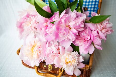 The beauty of a pink peonies bouquet in a vintage authentic brown suitcase, closeup. Beautiful composition.の写真素材