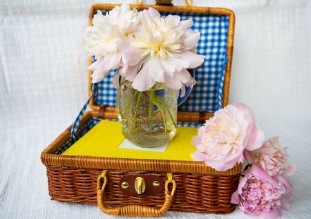 A very beautiful bouquet of pink peonies stands in a vase on a wooden suitcase. Beautiful composition.の写真素材