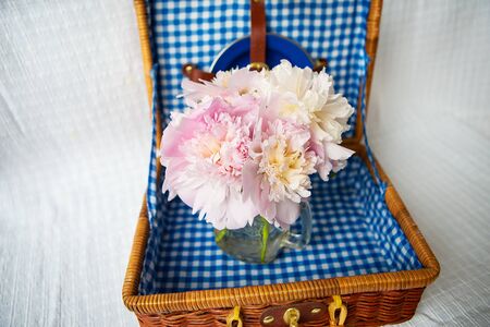 A very beautiful bouquet of pink peonies stands in a vase on a wooden suitcase. Beautiful composition.の写真素材
