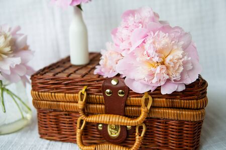 A very beautiful bouquet of pink peonies in a vase stands on a wooden suitcase. Beautiful composition. Close-up.の写真素材
