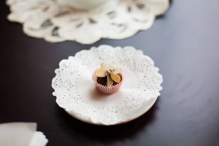 chocolate candy decorated with slices of nuts lying on a white plate.の写真素材