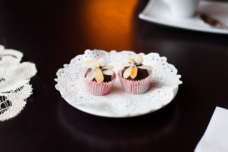 chocolate candy decorated with slices of nuts lying on a white plate.の写真素材