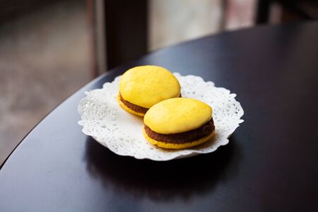 yellow macaroons lie on a white plate on a wooden table.の写真素材