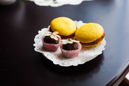 yellow macaroons and chocolate sweets lie on a white plate.の写真素材