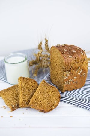 sliced bread on a napkin and a board, a glass of milk, a dry wheat-close-up.